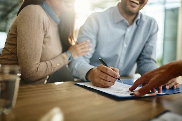 Close up of unrecognizable couple signing a contract in the office.