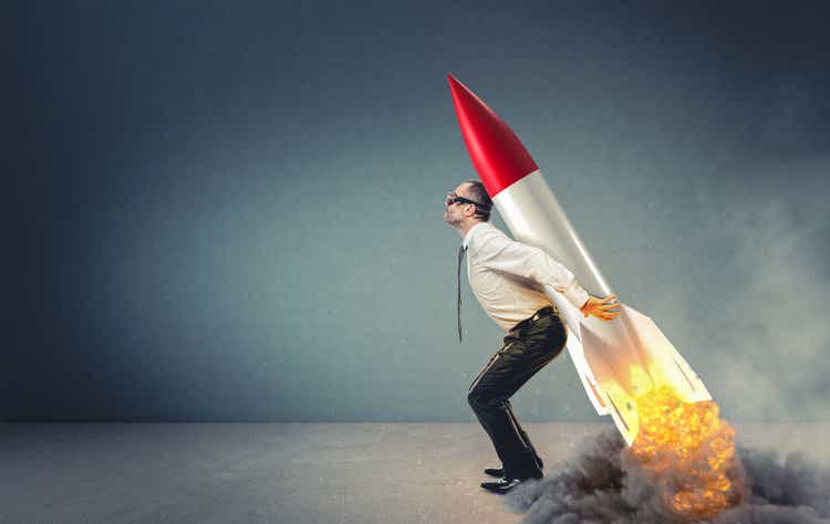 businessman with rocket on his back ready to take off.