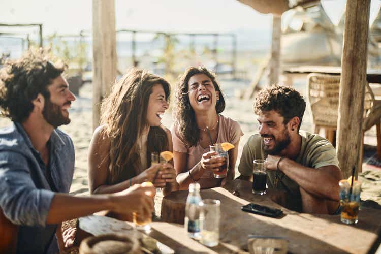 Cheerful couples talking in summer day at a beach bar.