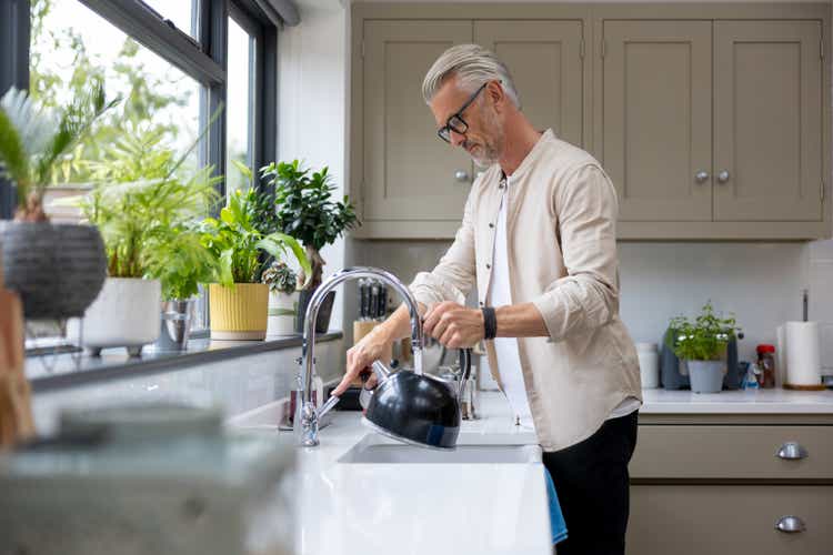Man makign a cup of tea and putting the kettle on