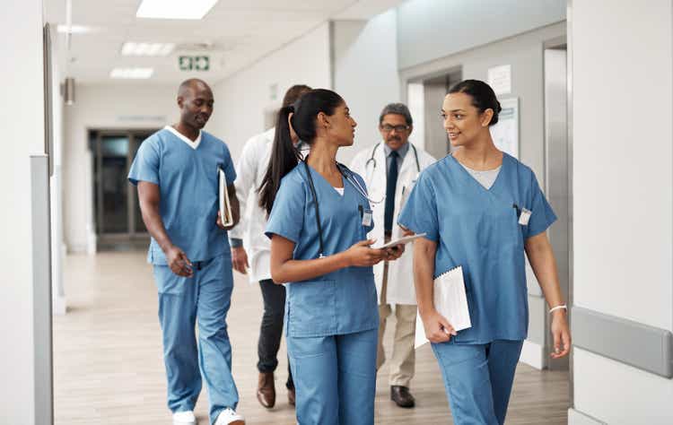 Doctor, nurse and walking hospital team after success surgery, medicine meeting or clinic insurance planning. Diversity workers, smile and happy medical healthcare teamwork on treatment collaboration