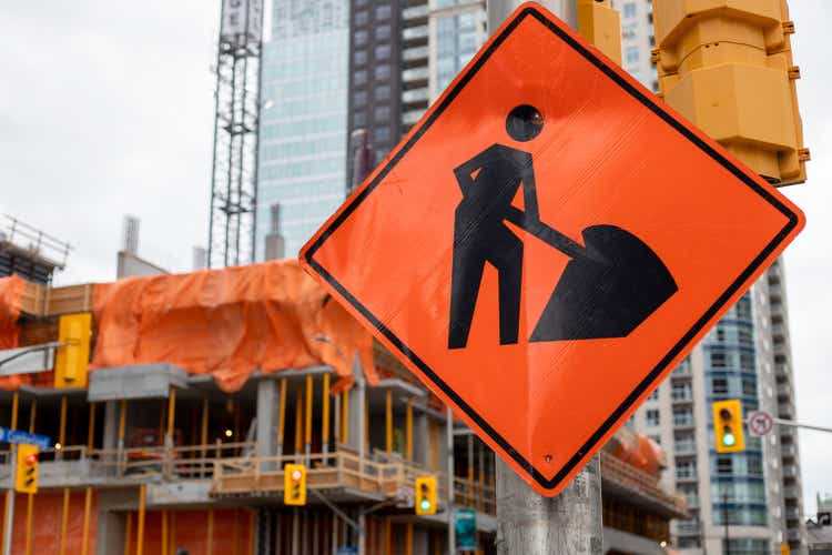 Construction orange road sign near construction site against buildings