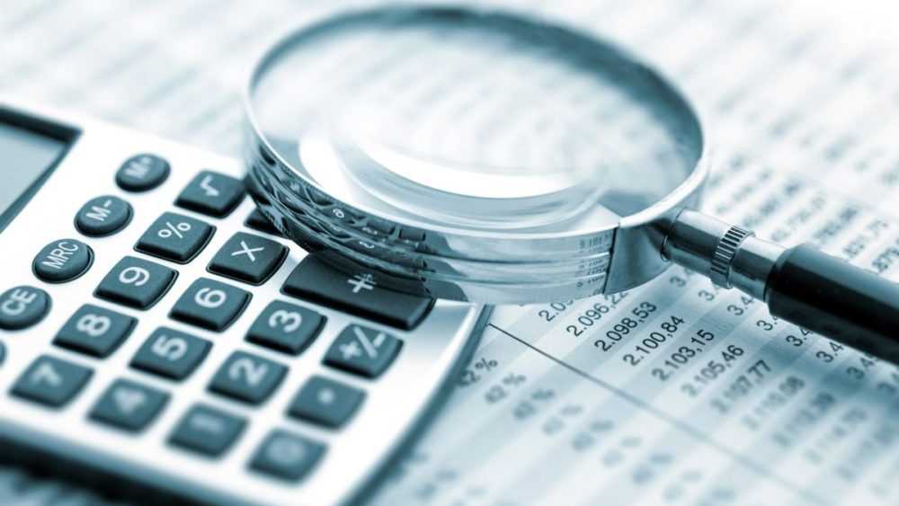 A magnifying glass rests on a calculator atop a paper chart.