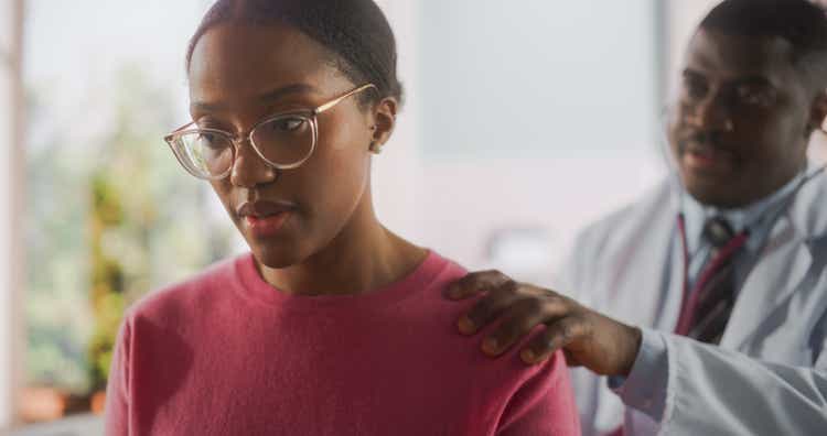 Portrait of a Professional Black Physician Using Stethoscope to Diagnose Any Lung Issue of a Recovering Young African Patient that Came for Check Up to a Modern Hospital After a Successful Surgery