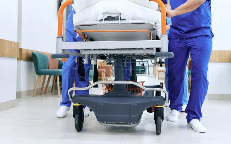Medical staff pushing patient on medical gurney at emergency department, bottom view. Hospital emergency and healthcare workers