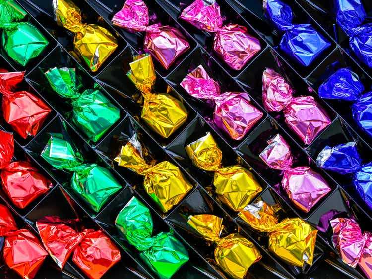 chocolate candies in shiny wrapper of different colors in regular order on a dark background