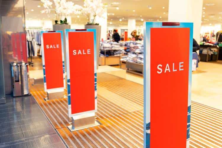 Red bright sale banner on anti-thieft gate sensor at retail shopping mall entrance. Seasonal discount offer in store