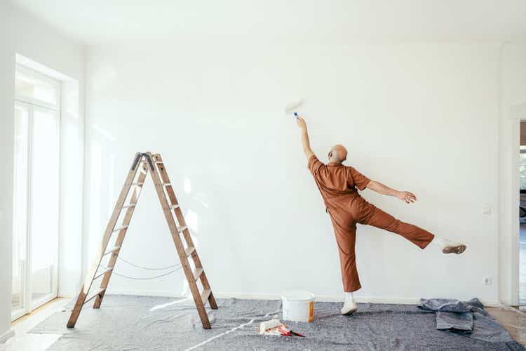 Young man having fun while painting the wall of his new house