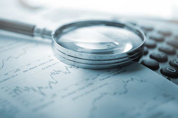 Magnifying glass, calculator and charts on paper