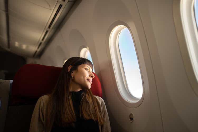 Young woman traveling by plane looking out the window