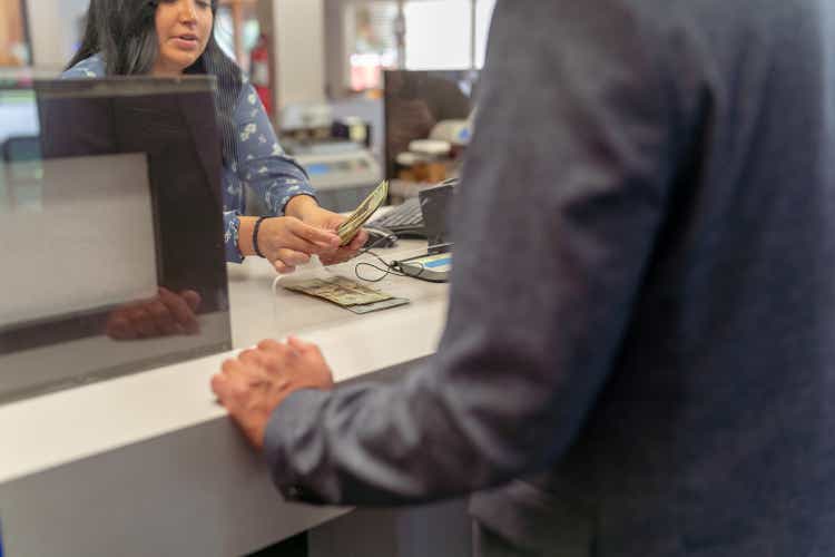 Bank teller counting money for customer