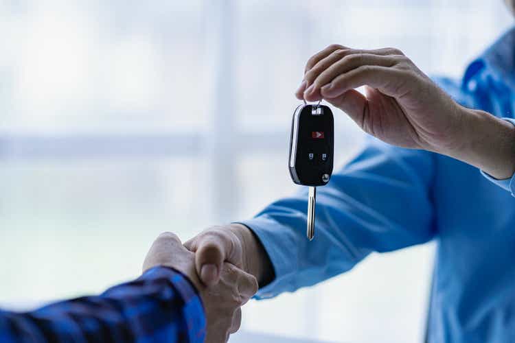 Крупный план продажи автомобиля и покупатель пожимают руки Продавец автомобилей дает ключи покупателю Крупный план автосалона дает ключи новому владельцу и рукопожатие в офисе