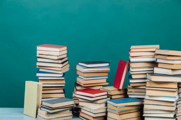 Стопки книг для преподавания знаний в библиотеке колледжа на зеленом фоне