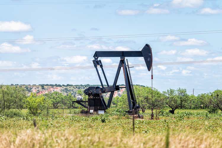Нефтяная насосная станция Свитуотер, Техас на нефтяных месторождениях в прериях с металлической машиной в поле в солнечный летний день с голубым небом и никого в пейзаже