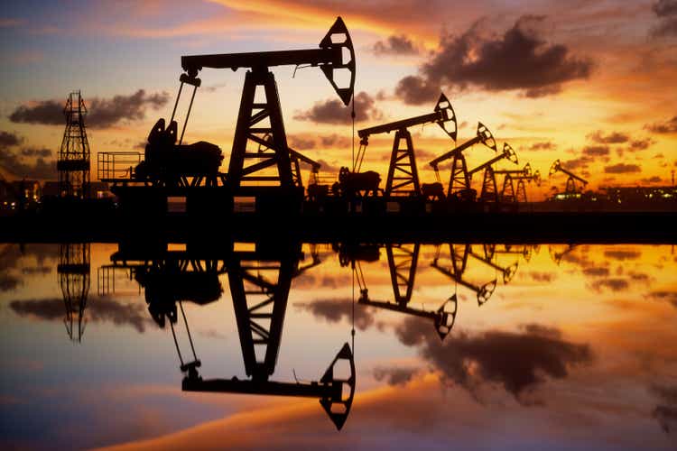 Нефтяные насосы и буровая установка на закате у моря
