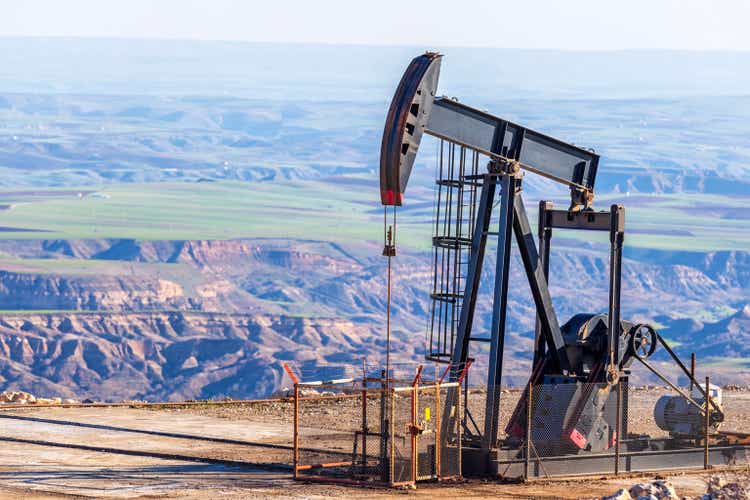 Вид на насосную станцию ​​в нефтяной скважине нефтяного месторождения.  Такое устройство обычно используется для наземных скважин, добывающих мало нефти.  Это надземный привод поршневого насоса в нефтяной скважине.