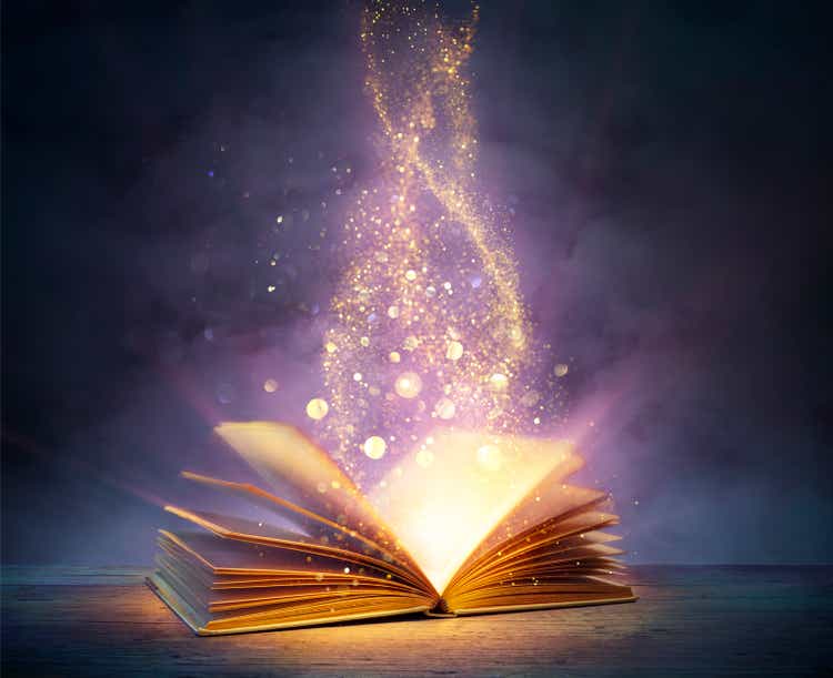 Волшебная книга с открытыми страницами и абстрактными огнями, сияющими в темноте - концепция литературы и сказки