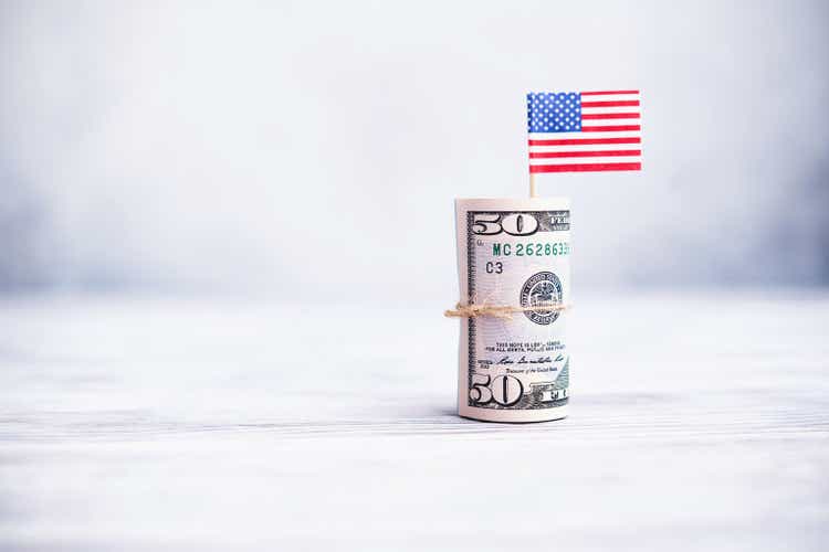 Большой денежный рулон американских долларов с американским флагом