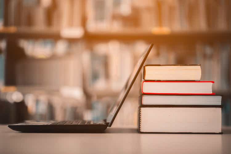 Книжные полки и ноутбуки размещены на библиотечном столе. Класс электронного обучения и цифровые технологии электронных книг.