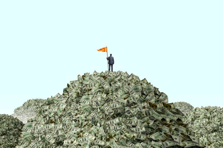 Мужчина устанавливает флаг на куче денег