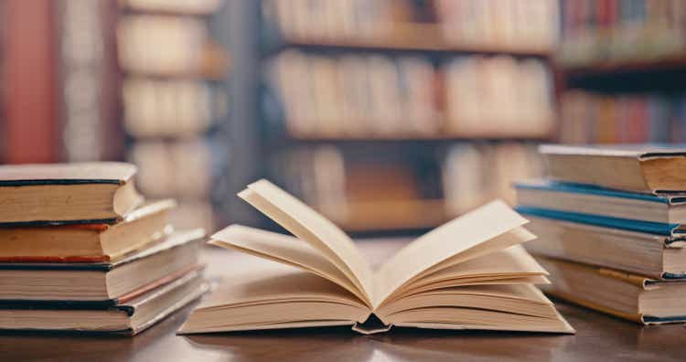 Библиотека, книги на столе и фон для учебы, обучения и исследований в сфере образования, школы или колледжа.  Чтение, философия и открытая, винтажная или историческая печатная книга, университетский размытый фон