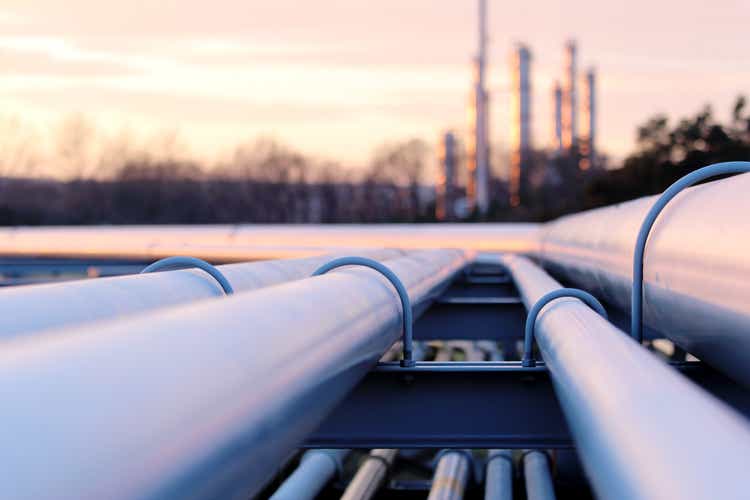 стальные длинные трубы на заводе сырой нефти во время заката