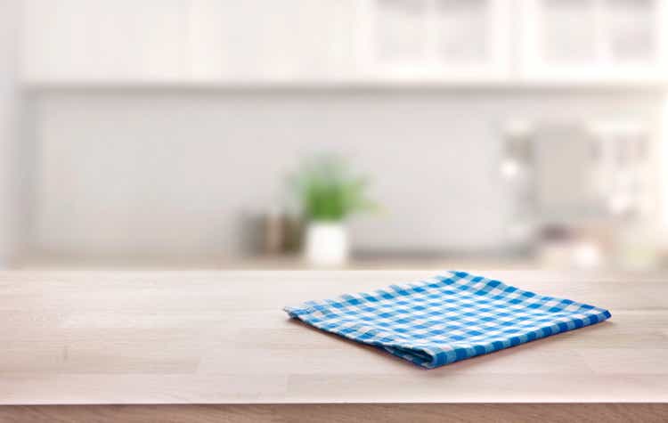 Blue folded kitchen napkin on wooden table. Towel on tabletop. Food advertisement design backdrop.