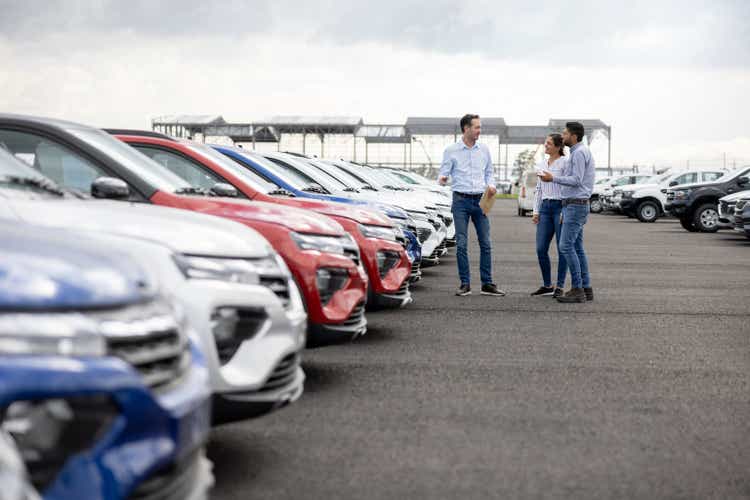 Продавец показывает автомобили паре в автосалоне