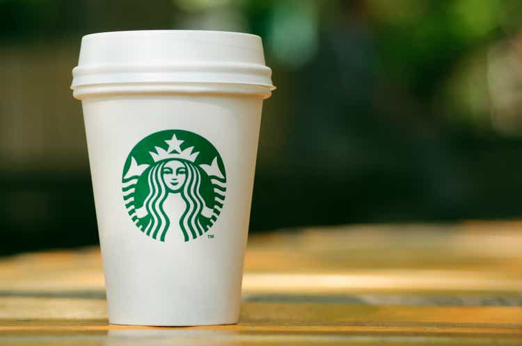 Высокий Starbucks принесет чашку на деревянный стол