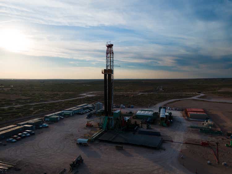 Сумеречный снимок буровой установки для гидроразрыва нефти под драматическим закатным небом в Пермском бассейне в Западном Техасе или Нью-Мексико