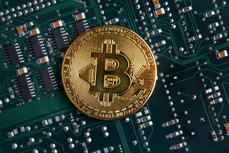 Золотая монета Биткойн на зелено-черной компьютерной схеме.