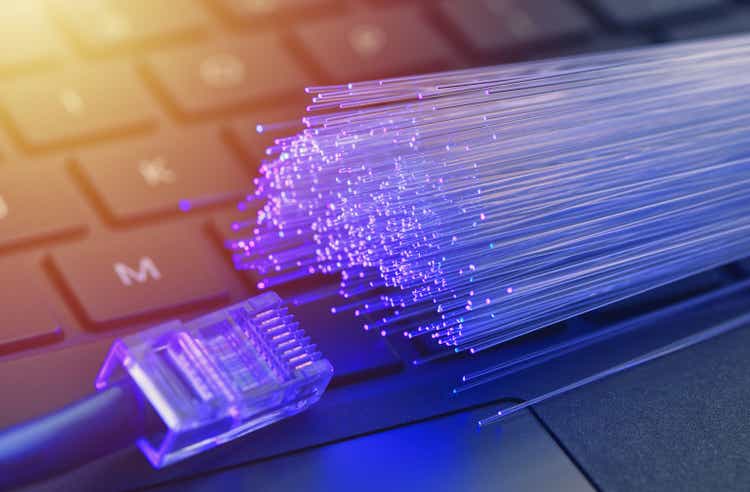 Волоконная оптика синего цвета, крупным планом на фоне Ethernet и клавиатуры, теплые блики линз