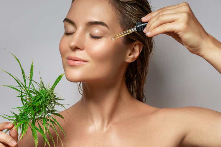 Концепция косметики CBD. Красивая женщина с листом конопли