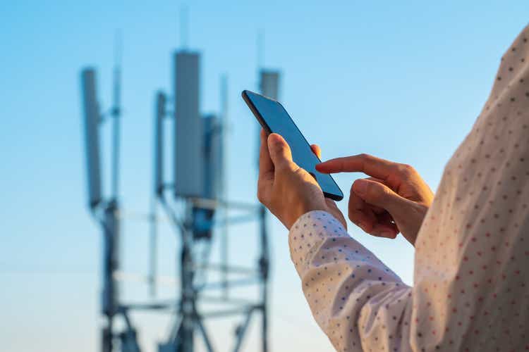 Башня связи 5G с мужчиной, использующим мобильный телефон