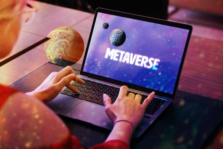 Концепция Метавселенной. Женщина использует ноутбук с экраном планеты