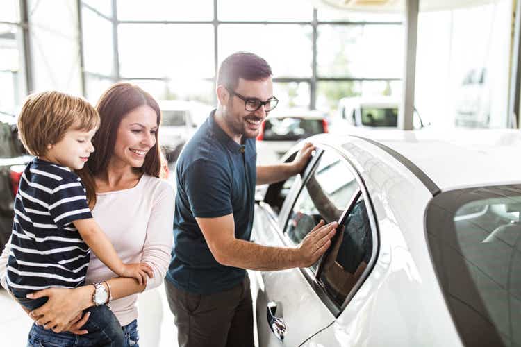 Счастливая семья выбирает новую машину в автосалоне.