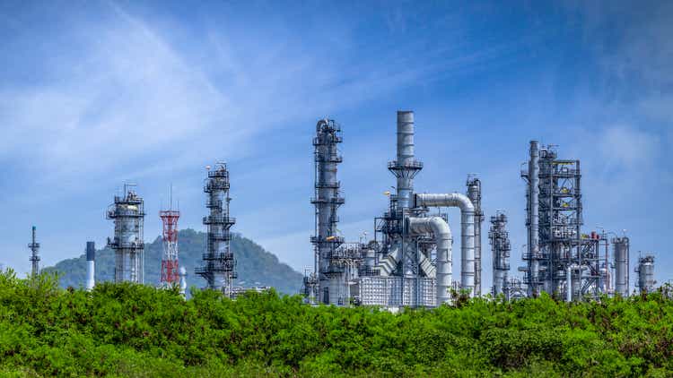 Нефтеперерабатывающий завод из промышленной зоны, Нефтегазо-нефтехимическая промышленность на фоне деревьев и голубого неба, Резервуар для хранения нефти и трубопроводная сталь нефтеперерабатывающего завода, Концепции экосистемы и здоровой окружающей среды.